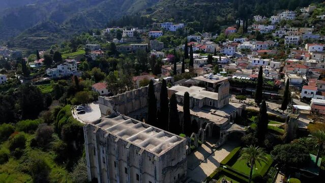 Aerial 4K view of beautiful Bellapais Village with Bellapais Monastery in Kyrenia, North Cyprus surrounded with an amazing green Mediterranean nature and picturesque landscapes in Cyprus.