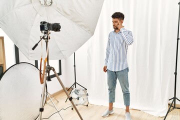 Arab young man posing as model at photography studio pointing unhappy to pimple on forehead, ugly...