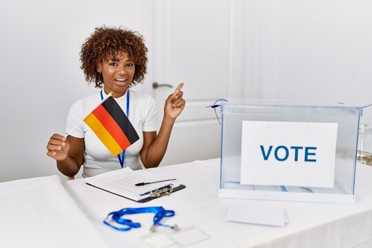 Young african american woman at political campaign election holding germany flag smiling happy pointing with hand and finger to the side