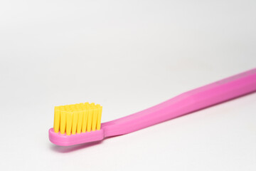toothbrush with pink handle yellow brush head. Toothbrush closeup on white background.
