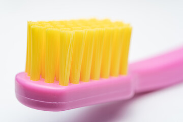toothbrush with pink handle yellow brush head. Toothbrush closeup on white background.