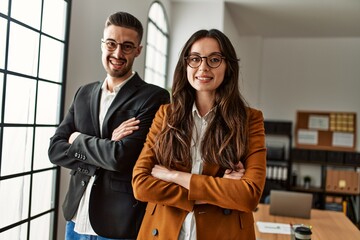 Two business workers smiling happy standing with arms crossed gesture at the office.