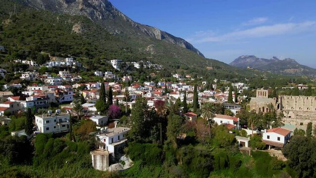 Aerial 4K view of beautiful Bellapais Village with Bellapais Monastery in Kyrenia, North Cyprus surrounded with an amazing green Mediterranean nature and picturesque landscapes in Cyprus.