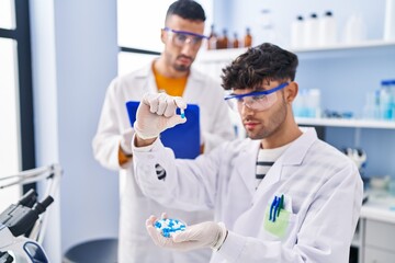 Two man scientists holding pills write on clipboard working at laboratory