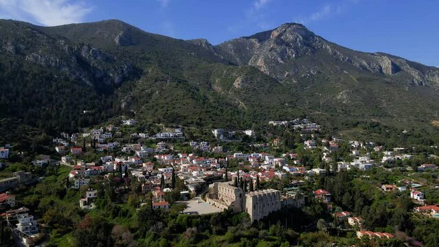 Aerial 4K view of beautiful Bellapais Village with Bellapais Monastery in Kyrenia, North Cyprus surrounded with an amazing green Mediterranean nature and picturesque landscapes in Cyprus.