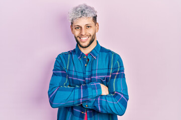 Young hispanic man with modern dyed hair wearing casual retro shirt happy face smiling with crossed arms looking at the camera. positive person.