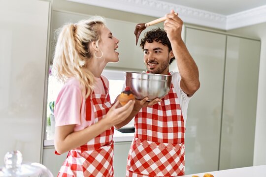 Young couple smiling happy cooking sweets at kitchen.