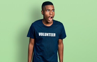 Young african american man wearing volunteer t shirt angry and mad screaming frustrated and...