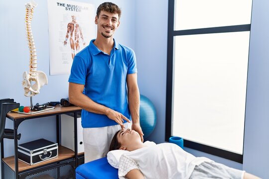 Man and woman wearing physiotherpy uniform having reiki therapy session at clinic