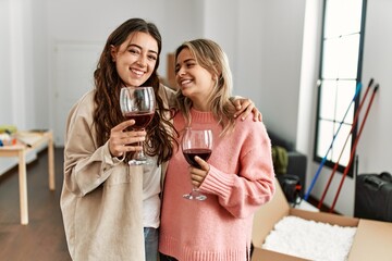 Young couple smiling happy toasting with red wine at new home