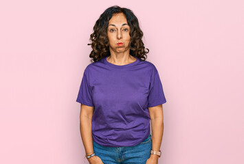 Middle age hispanic woman wearing casual clothes puffing cheeks with funny face. mouth inflated with air, crazy expression. - obrazy, fototapety, plakaty