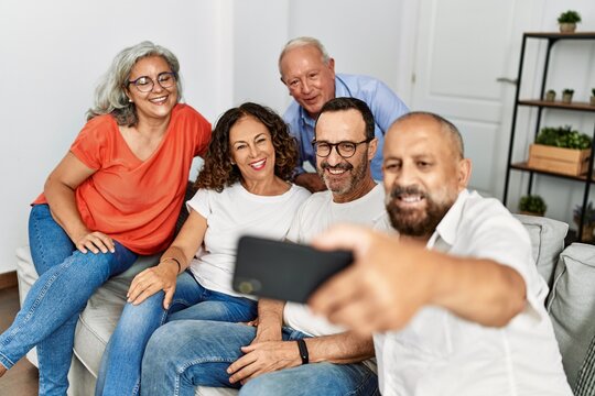 Group of middle age friends smiling happy make selfie by the smartphone at home.