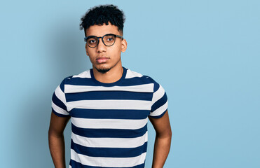 Young african american man wearing casual clothes and glasses relaxed with serious expression on...