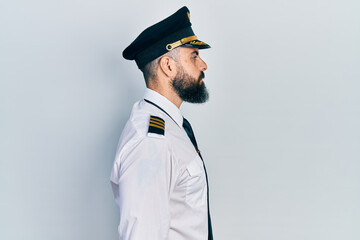 Young hispanic man wearing airplane pilot uniform looking to side, relax profile pose with natural face with confident smile. © Krakenimages.com