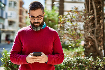 Young hispanic executive man smiling happy using smartphone at the city.