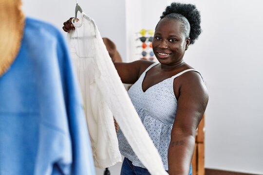 Young african american woman customer holding clothes of rack at clothing store