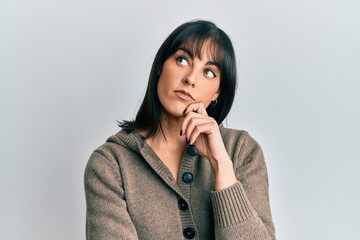 Young hispanic woman wearing casual clothes thinking concentrated about doubt with finger on chin...
