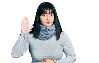 Young hispanic plus size woman wearing winter scarf swearing with hand on chest and open palm,...