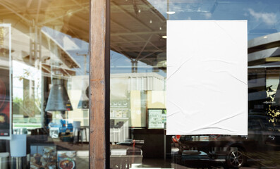 Mockup white paper or white sticker poster displayed on the front of the restaurant, coffee shop,...