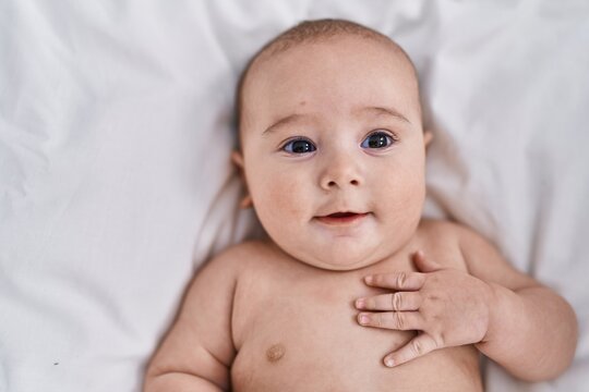 Adorable baby smiling confident lying on bed at bedroom