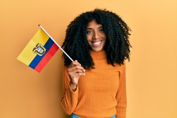 African american woman with afro hair holding ecuador flag looking positive and happy standing and smiling with a confident smile showing teeth - obrazy, fototapety, plakaty