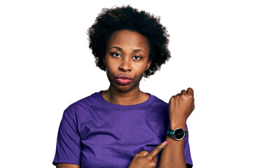 African american woman with afro hair wearing casual purple t shirt in hurry pointing to watch...