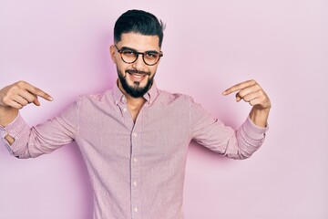 Handsome man with beard wearing casual shirt and glasses looking confident with smile on face,...