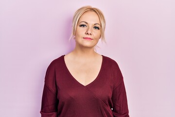 Young blonde woman wearing casual winter sweater relaxed with serious expression on face. simple and natural looking at the camera.