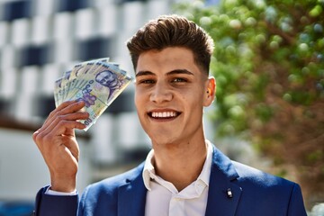 Young man wearing suit holding romania lei banknotes at park