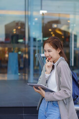 Asian woman publicly uses their laptop to study and work outdoors in shopping malls.