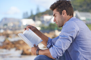 Novels are a great way to relax. A young man reading a book outdoors.