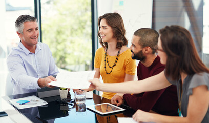 Heres the paperwork you asked for. Cropped shot of a group of businesspeople in a meeting.