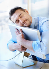 Its his best friend in the office. Shot of a smiling businessman hugging his monitor warmly.