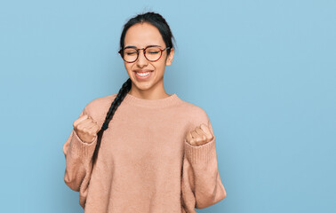 Young hispanic girl wearing casual clothes and glasses very happy and excited doing winner gesture...