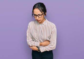 Young hispanic girl wearing casual clothes and glasses with hand on stomach because indigestion,...