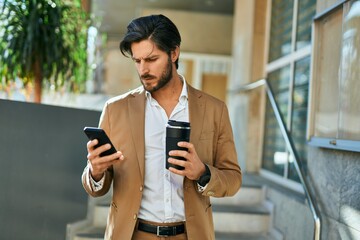 Young hispanic businessman using smartphone and drinking coffee at the city.