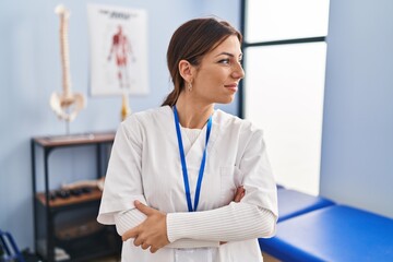 Young brunette woman working at pain recovery clinic looking away to side with smile on face, natural expression. laughing confident.