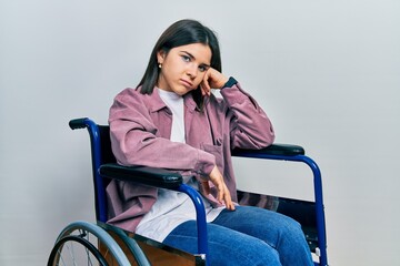 Young brunette woman sitting on wheelchair thinking looking tired and bored with depression...