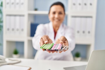 Middle age hispanic woman wearing doctor uniform prescribe pills at clinic