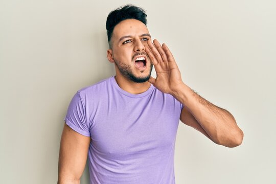 Young arab man wearing casual clothes shouting and screaming loud to side with hand on mouth. communication concept.