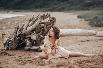 A girl in a pale pink raincoat and a white T-shirt walks alone along the sandy beach