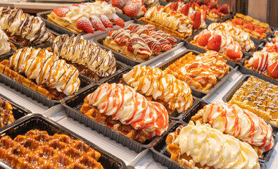 Delicious traditional Liege waffles with colorful toppings on display in a store window in Brussels, Belgium. Sugary desserts. Typical Belgian sweet food.