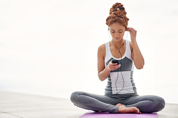The perfect accompaniment to her yoga session. Shot of a young woman listening to music while...