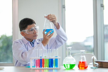 Little boy mixes chemicals in beakers. kids with test tube making experiment at school laboratory.