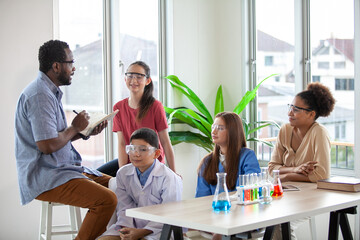 Student raising a hand with a question for the teacher. Teacher pointing at student with hand raised in science classroom.