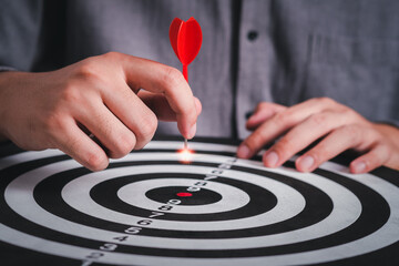 Hand holding dart arrow hit in target center of dartboard, successful business concept. Executive...