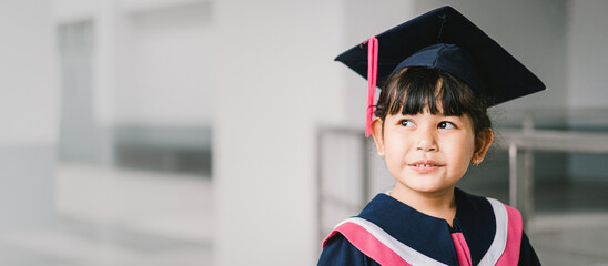 Portrait of a cute Asian graduated schoolgirl with graduation gown in school