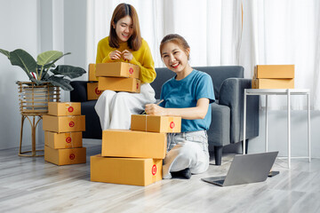 Fototapeta na wymiar Two Asian Young business woman on sofa at home. startup sme small business entrepreneur SME distribution warehouse with parcel mail box. SME Online marketing and product packaging and delivery service