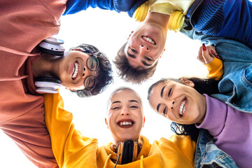 Low angle view of teen college student hug with heads in circle. High school friends smiling...
