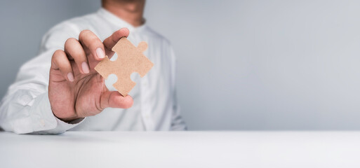 A one jigsaw puzzle element in a businessman's hand. Person hand showing a piece of the important...